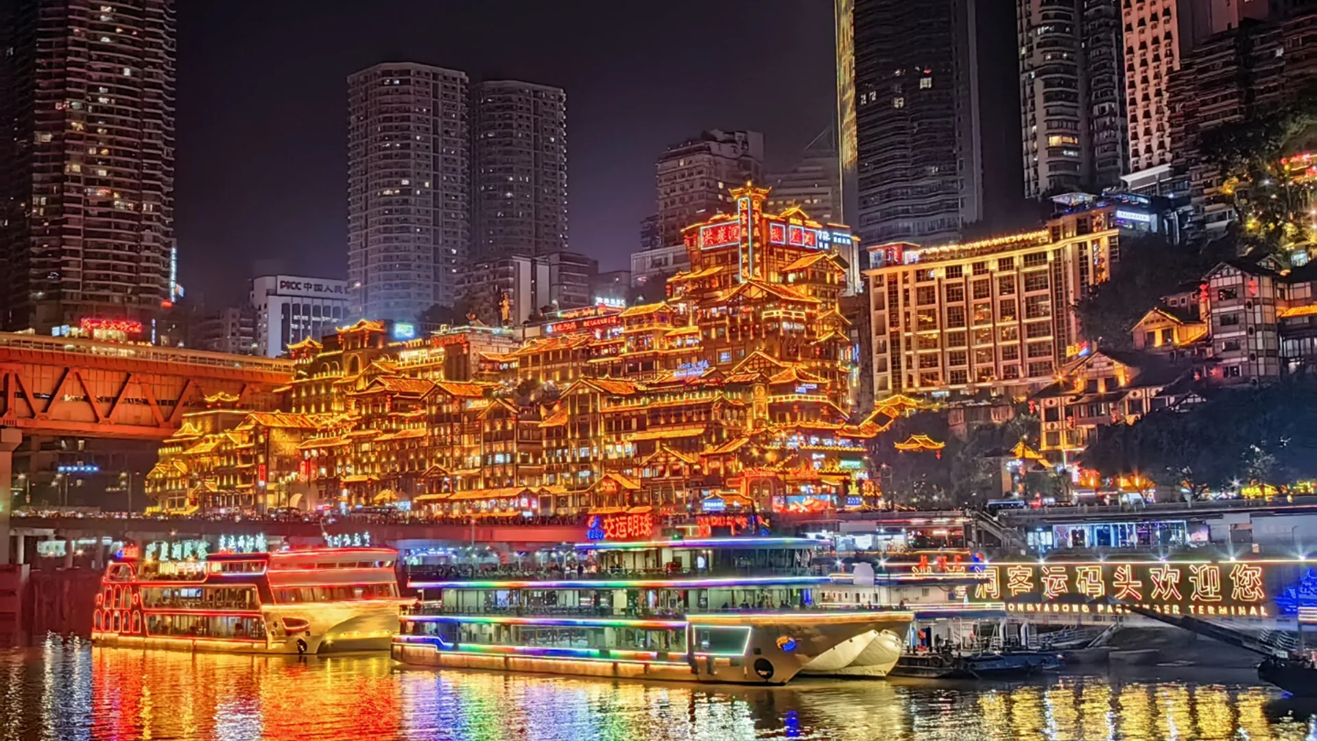 Hongyadong's illuminated buildings below taller towers on Chongqing's riverfront.