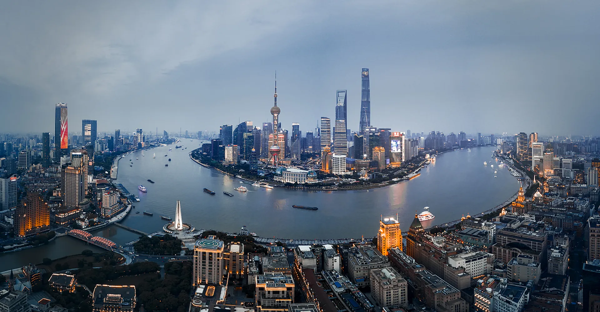 An elevated view of Shanghai's Huangpu River, the Bund, and Pudong skyline.