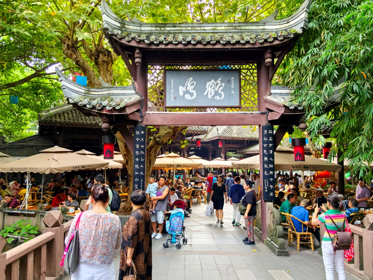 Visitors walking through the tiled entrance of Heming Teahouse, with outdoor tea tables on both sides.
